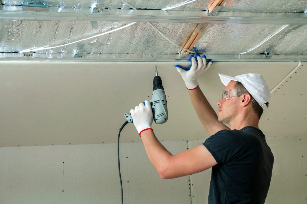 Montážník upevňuje stropní panel pomocí elektrického nářadí